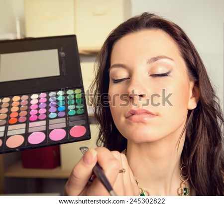 In the beauty salon. Girl doing makeup. Cosmetics and color palette for makeup. Cosmetics, woman, fashion, beauty, care, face, glamor, trend - the concept of a modern lifestyle. Work up artist.