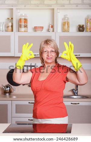 Adult woman makes cleaning the kitchen. Woman in yellow gloves cleaning the kitchen. Cleanliness, order, shine, clean, shiny, cleaning after the holidays at home kitchen. attractive middle aged woman.