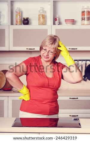 Adult woman makes cleaning the kitchen. Woman in yellow gloves cleaning the kitchen. Cleanliness, order, shine, clean, shiny after the holidays at home kitchen. Attractive middle aged woman. vintage