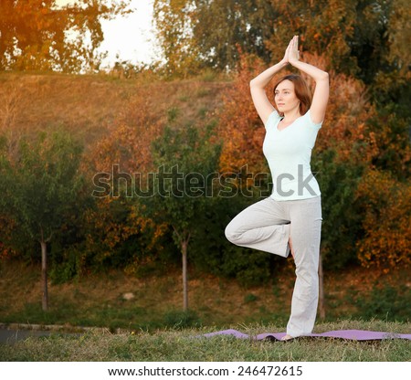 Woman practicing yoga pose outdoors over sunset sky background. Woman doing yoga poses outdoors at sunset with lens flare. Female fitness training outdoor. Healthy lifestyle image of woman outside.