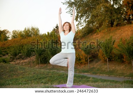 Woman practicing yoga pose outdoors over sunset sky background. Woman doing yoga poses outdoors at sunset with lens flare. Female fitness training outdoor. Healthy lifestyle image of woman outside.