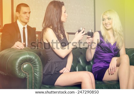 Complicated love relationship between three people. Woman looks at another woman. Two women drinking wine and turned his back on the man. Party at the club. Jealous man his woman. Mistress and lover.