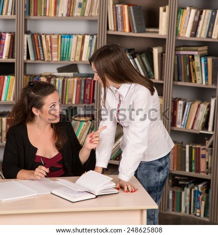 Conversation women office. Two young businesswomen having a meeting in the office sitting at a desk having a discussion with focus. Two girls students discuss course material. Female business.