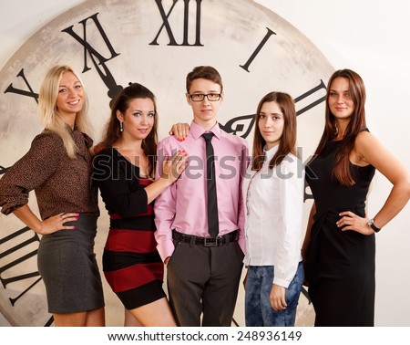 Cheerful business group. Four women and one man were gathered together. Students in practice, working in the office. Group of people of different nationalities on the background of the clock.