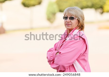 Adult woman on the blur background. Senior woman in tracksuit enjoying life. Fitness classes in the open air. Fitness, rehabilitation, senior, woman, sport, fitness - concept lifestyle adult retired.