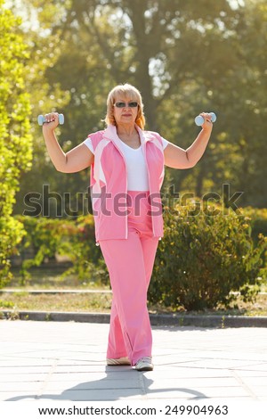 Adult woman playing sports and fitness in the city park in the morning. Senior people, old woman during sports training in the park. Senior woman exercising in park. Mature woman active. Middle aged.