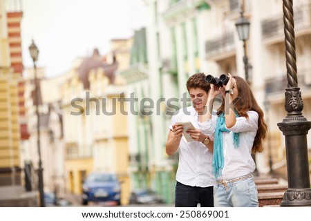 Man and woman traveling through the beautiful old city of Europe. Happy couple tourists with map and binoculars, a walk through the historic center of the city. Summer holidays, love and relationship.