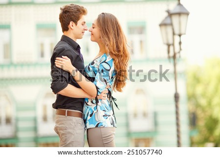 A pair of lovers people on the city walk. The love story of two young people. Man and woman embracing each other. Walking through the city summer day. Feelings of love between two people. Love story.
