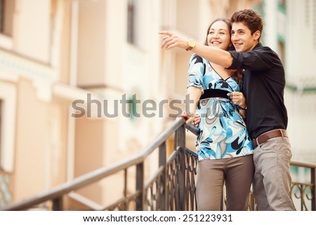 Man points a finger at hand in the direction of something interesting. Love story man and woman who travel to city. Man embraces woman and she is very happy. Joy, love is mutual feelings of two people