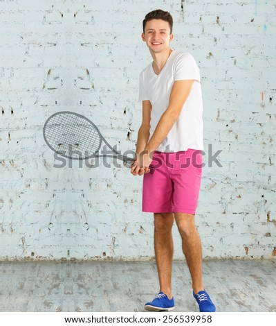 Dream to play tennis. Dreams come true. Male athlete in a white shirt and pink shorts on the brick wall background. Modern young man. Silhouette tennis racket in hand. Get credit for dreams. Sport