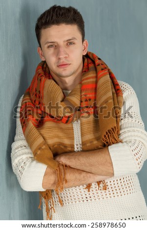 Stylish man. Young man. Close up. Portrait of young man in white blouse with striped scarf over gray background. Studio shot. Young confident man looking directly. Ordinary people.