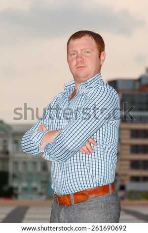 Man in a plaid shirt on the background of the city. A man with red hair. Business man on background downtown