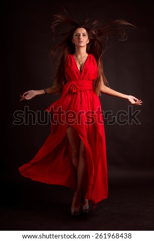 Beautiful woman in red dress. National beauty woman in a flowing red dress and hair developing on a wind. Studio photography. Harvesting concept for design. Layout for advertising.