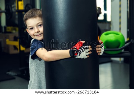 Boy - box, fitness, sport. Young boy standing by bag boxing. The boy has been in the gym for boxing. Young man in a sports hall near the bag for boxing. Simulator. Trainer.