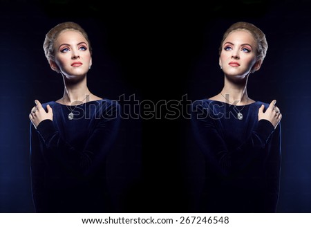 Woman in a blue dress on a background of blue blue glow of light. Beautiful noble woman of aristocratic origin with a mirror reflection of her again. Photo portrait of woman on a dark blue background.