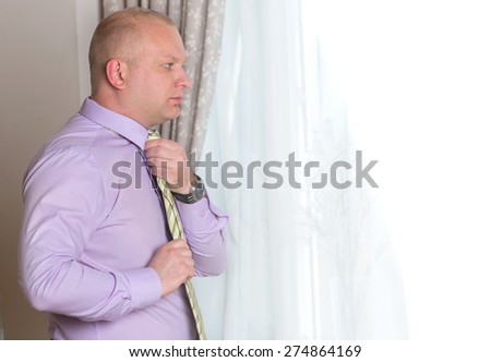 Adult business man going to a meeting. In the morning a man is going to work. He ties a tie buttoning a shirt sleeve. Groom prepare for the wedding. Man in suit correcting a sleeve. Man in hotel room