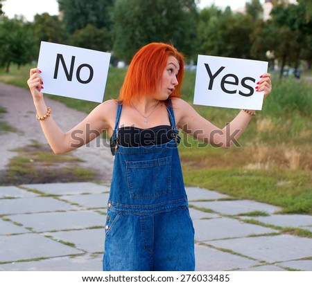 Girl holding signs for the words yes and no. She makes the choice. Woman on the background nature. Red hair girl holding a white sheet of paper two. Happy woman smiling portrait. Funny emotions. Life.