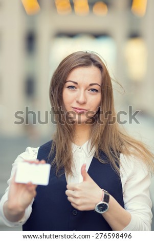 Business card in the hands. Woman stretches forward a business card. Business card in a hand against a blurred background body business people. Businesswoman showing and handing a blank business card.