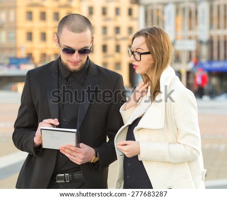 Businessman and businesswoman meeting. Business meeting manager and the client on the background of business office buildings downtown. They discuss the contract or insurance policy. Business people.