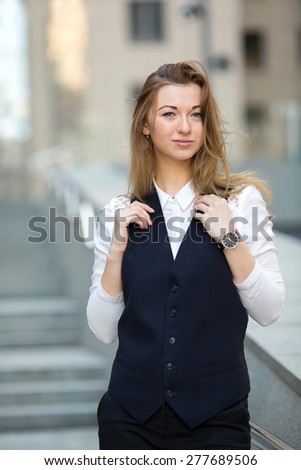 Young modern woman. She is office worker. Business woman broker, salesman. Business woman on the background of an office building. She works as a sales manager, agent, marketer. Student woman.