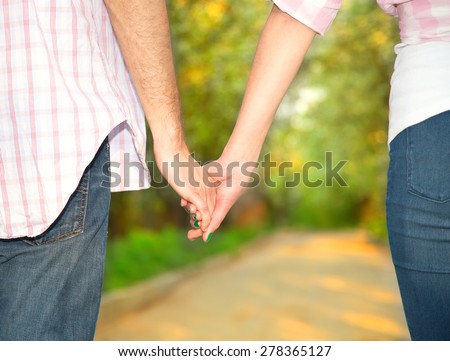 Clasping hand lover. Men and women in park. Concept of love story and family story. Hands of lovers, close up. Couple holding hands on sunset background.
