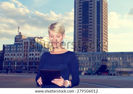 Businesswoman with digital tablet in the city. European woman using tablet pc computer outdoor on a city street. Business woman with tablet pc in office district.
