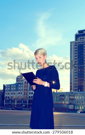 Businesswoman with digital tablet in the city. European woman using tablet pc computer outdoor on a city street. Business woman with tablet pc in office district.
