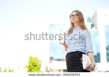 Urban woman commuter walking drinking coffee. Business woman in the city. Cheerful woman in the street drinking morning coffee. Happy young trendy woman drinking take away coffee and walking with bags