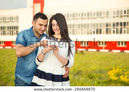 Young couple, man and woman together on the background of the city. Woman holding a cell phone. They talk or check messages in your phone. Men and women of Asian or Arab origin. Modern communication.