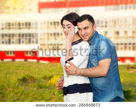 Young couple, man and woman together on the background of the city. Woman holding a cell phone. They talk or check messages in your phone. Men and women of Asian or Arab origin. Modern communication.