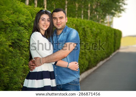 Love Story. Young man and woman together. Multiethnic couple in love. Walk a summer day in the city or in the park where the many green plants. They trips after the wedding. Joint experience emotions