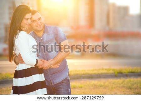 Love story, man and woman, love - concept of human life in a big modern city. Couple in love in the glow of the sunset on the background of urban buildings. Display a sense of love for each other.