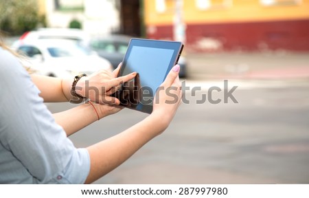 Two woman using touch pad. Close up young female student using touch pad on the city background, freelancer girl working on her digital tablet with big copy space. Two women with touchscreen device.