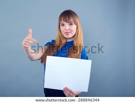 Happy woman holding a white banner and smiling. Woman hold white paper banner. Young smiling woman show blank board. Female model portrait on blue background. Concept - insert labels, ads. She shows.