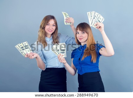 Two young women. Business emotional women hold in their hands the money, it's a lot of dollars. Two women earn money, they received their salary. Positive emotions for the right solution. Win lottery.
