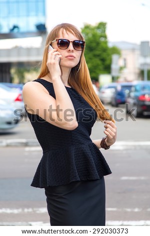 Young beautiful woman with sunglasses and phone. Young beautiful business woman calling by phone. Businesswoman, sunglasses, mobile phone - Concept for Mobile Advertising. Talking on a mobile phone.
