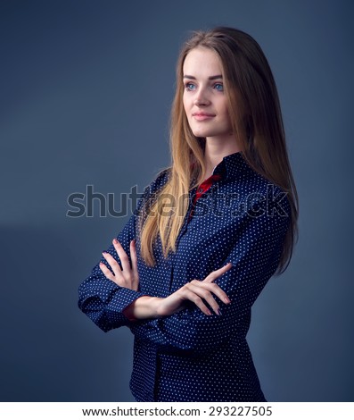Modern stylish young woman model standing on a dark background. Ordinary people can be a photo model. Portrait of a modern woman. Woman happy. Or a girl student. Women business posture, hands crossed.