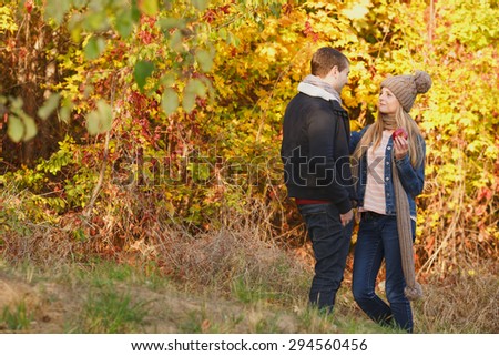 Happy couple in autumn garden. Happiness man and woman talking to each other. Girl offers apple guy together outdoors. Eat apples - healthy food. Love story of one autumn afternoon in the city park.