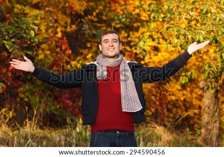 Happy man in the autumn city garden. Happy man with hands up on sunset background. Outdoor. Park. Man is relaxing on sunny autumn day at park background. Concept of well being and healthy lifestyle.