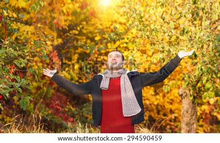 Happy man in the autumn city garden. Happy man with hands up on sunset background. Outdoor. Park. Man is relaxing on sunny autumn day at park background. Concept of well being and healthy lifestyle.