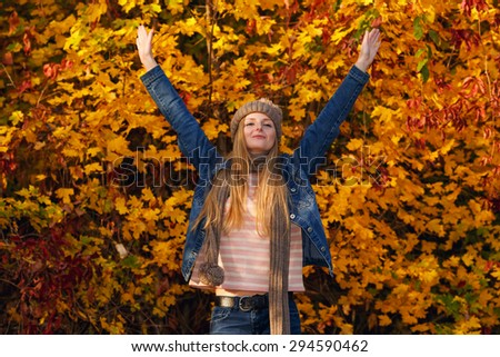 Happy woman in the autumn city garden. Happy woman with hands up on sunset background. Outdoor. Woman is relaxing on sunny autumn day at park background. Concept of well being and healthy lifestyle.