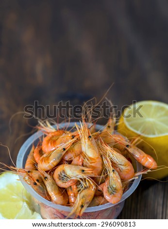 Shrimp from the Black Sea. Snack to beer and wine. Serve cooked shrimp and lemon on a bar table. Delicious fresh cooked shrimp prepared to eat. Cooked shrimps with lemon on wooden table.