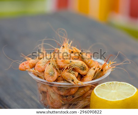Shrimp from the Black Sea. Snack to beer and wine. Serve cooked shrimp and lemon on a bar table. Delicious fresh cooked shrimp prepared to eat. Cooked shrimps with lemon on wooden table.