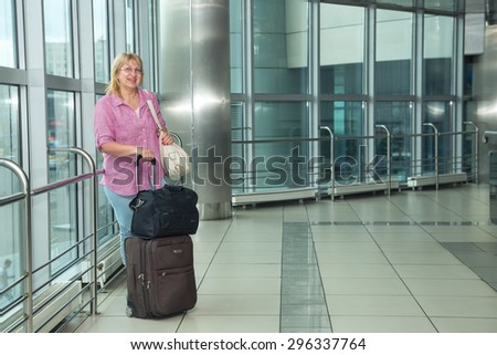 Adult woman is traveling. Woman with a suitcase goes on building the bus station, train station or airport. Retired woman embarks on a journey. Bags and suitcases for travel. Travel. Lifestyle.