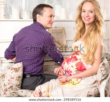 Happy family. Pregnant woman and her man. Pregnant happy smiling woman sitting on a sofa and caressing her belly. Mom expecting baby. Pregnancy. Beautiful pregnant woman and man. Maternity concept.