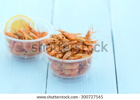 Shrimps. Sea products. Serving of cooked shrimp. Prepared shrimp on wooden blue background. Shrimp from the Black Sea. Snack to beer and wine. Delicious fresh cooked shrimp prepared to eat.