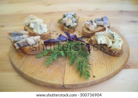 Sandwiches of rye bread and herring. Pieces of fish are herring on bread. Sandwiches with bread and fish on a wooden boards background. Traditional appetizer Scandinavian. Fish on the wooden board.
