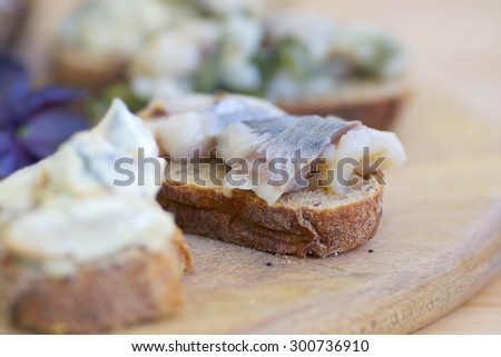 Sandwiches of rye bread and herring. Pieces of fish are herring on bread. Sandwiches with bread and fish on a wooden boards background. Traditional appetizer Scandinavian. Fish on the wooden board.