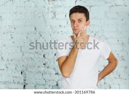 Emotional man. Man surprised, he learned the news. The emotions of surprise, wonder and think about what he knows. A man on a brick wall background light blue. Man not understand what was happening.