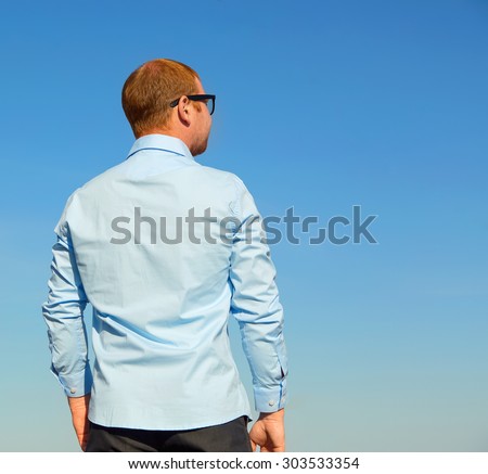 The man turned his back. Man standing and looking the skyline. Blue sky background.